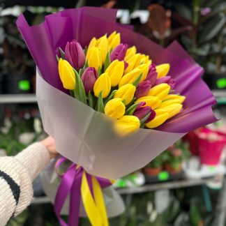 Яскравий мікс тюльпанів із 29 штук у пурпурово-жовтих тонах, елегантно оформлений у прозору упаковку з пурпуровим і жовтим декором